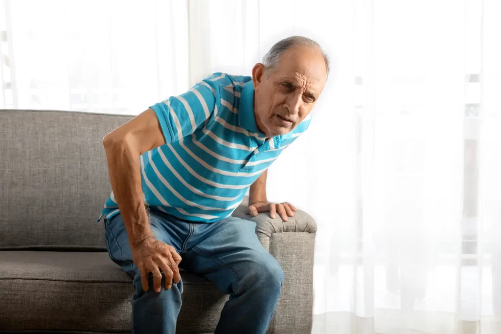 A senior man experiencing pain in his knee when standing up.