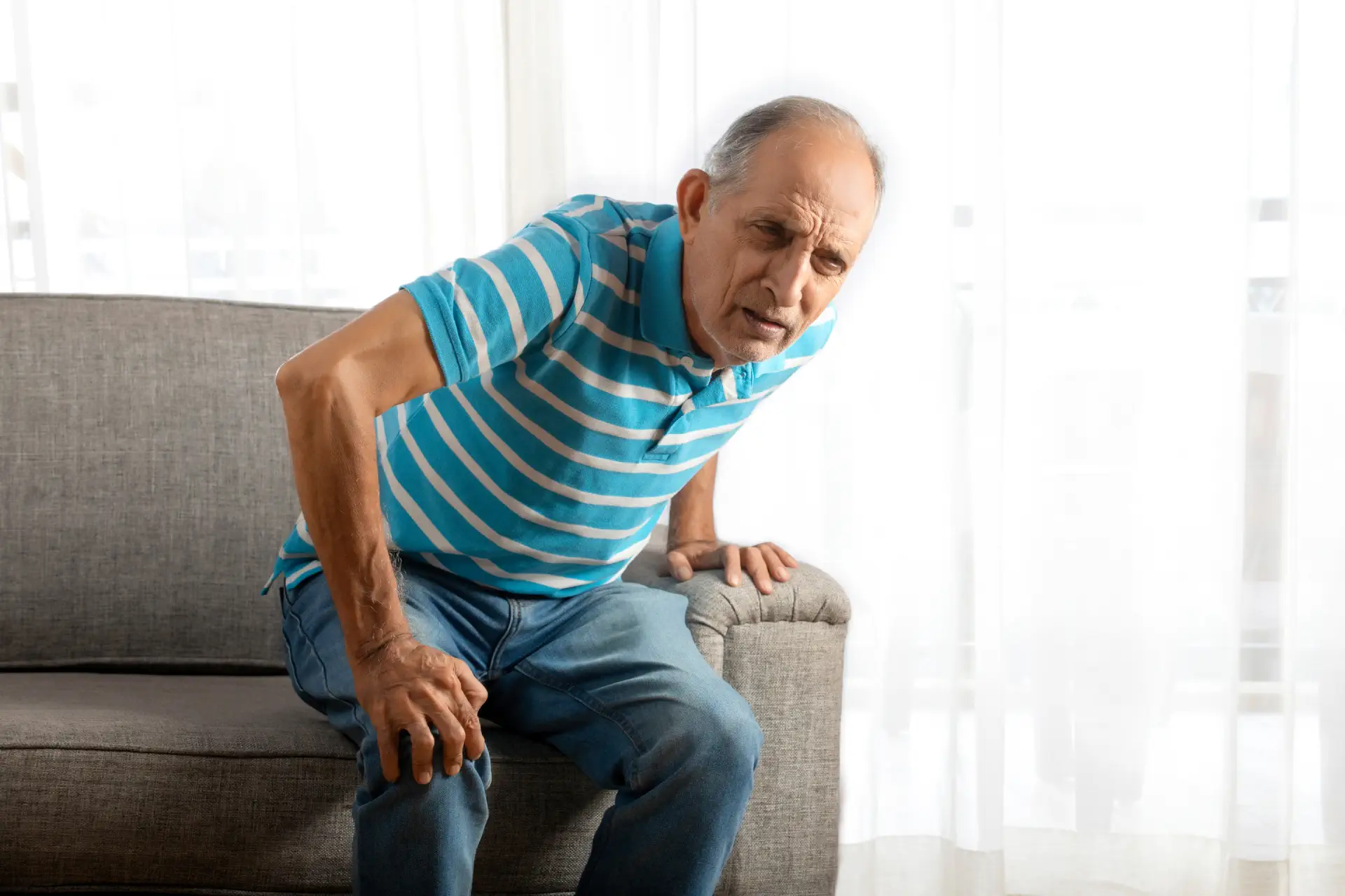 A senior man experiencing pain in his knee when standing up.